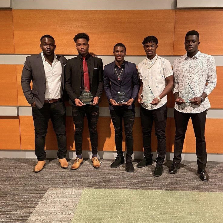 Men's Soccer players with Head Coach Oniqueky Samuels, showing off some awards. 
